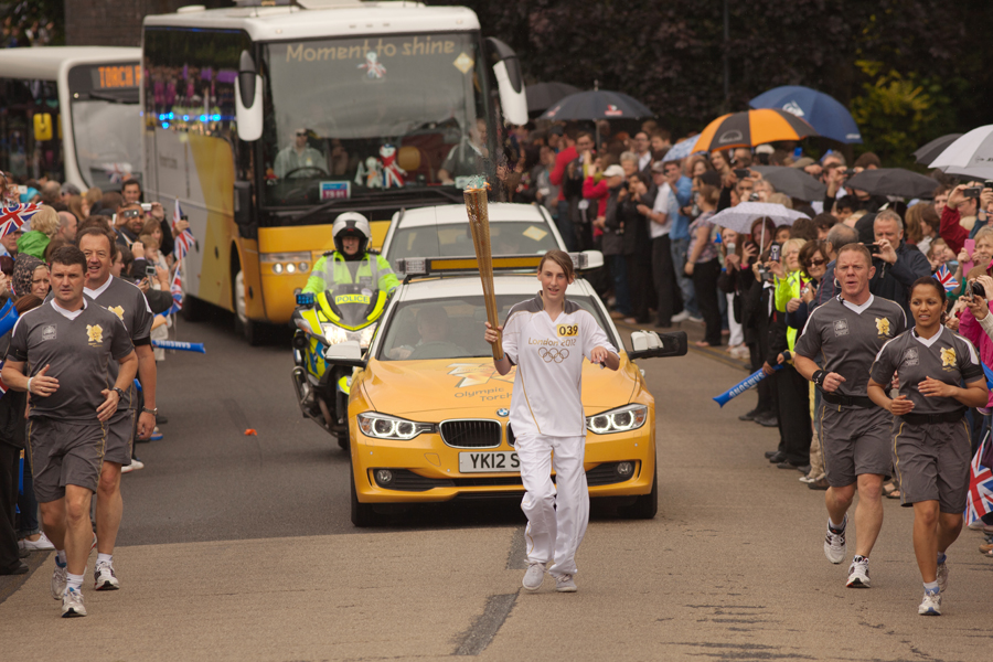 Flanked by the Torch Security Team, Abi Grainger holds the torch aloft