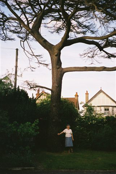 Grandma with the old cedar tree before it was cut down
